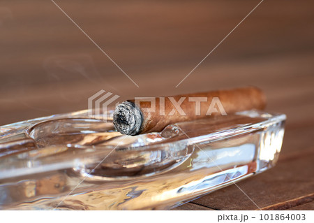 Burning Cuban cigar in a glass ashtray Burning Cuban cigar in a glass ashtray 101864003