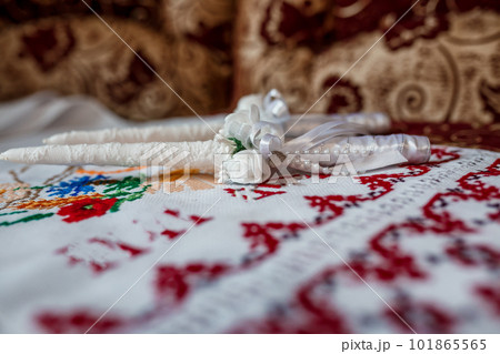 Wedding accessories on an embroidered towel, white candles for church, boutonnieres for guests Wedding accessories on an embroidered towel, white candles for church, boutonnieres for guests 101865565