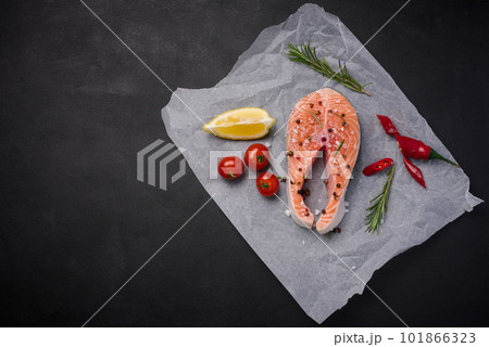 Raw piece of salmon with spices is lying on parchment paper, top view Raw piece of salmon with spices is lying on parchment paper, top view 101866323