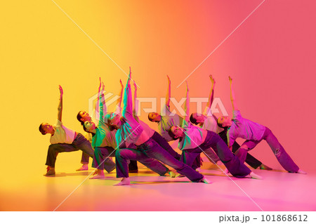 Group of beautiful teenage girls wearing white t-shirt and jeans dancing together on pink and yellow gradient background in neon light. Synchronicity 101868612