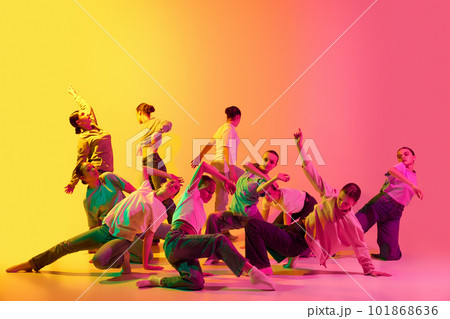 Group of teenagers, young dancers emotionally dancing together on pink and yellow gradient background in neon light. Girls dance club 101868636