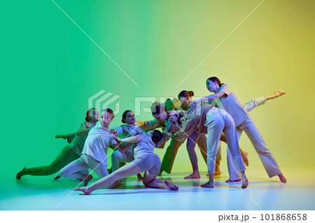Group of beautiful school girls wearing white clothes dancing together on gradient background in neon light. Contemporary dance style 101868658