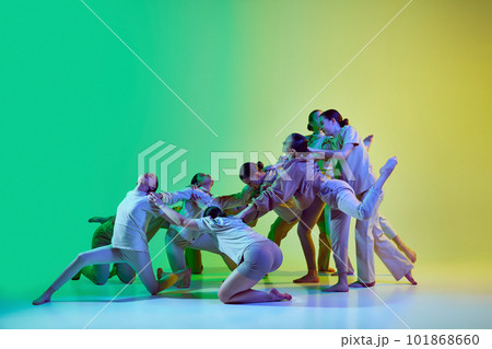 Group of teenagers, young dancers emotionally dancing together on gradient background in neon light. Modern dance style Group of teenagers, young dancers emotionally dancing together on gradient background in neon light. Modern dance style 101868660