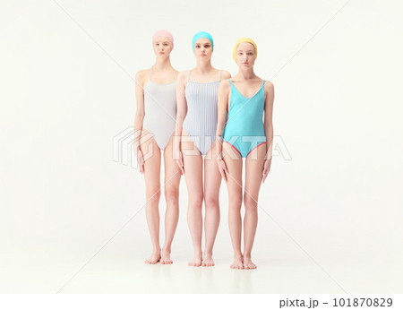 Three emotionless young girls with slim body standing in retro style swimsuits and swimmings caps isolated over white background 101870829