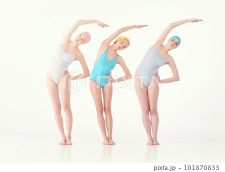 Stretching and warming-up. Three slim girls in retro style swimsuits and swimming cap isolated over white background 101870833