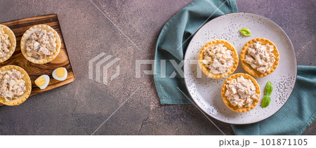 Tartlets filled with canned fish, eggs and mayonnaise on a plate top view web banner 101871105