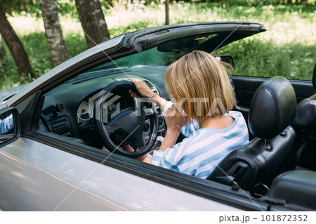 A woman is driving a convertible car. Summer road trip to nature 101872352
