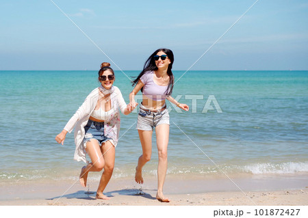 Happy female couple or bisexual couple enjoy walking along the beach together, women holding a hands together and running along the beach. LGBTQ people concept. Happy female couple or bisexual couple enjoy walking along the beach together, women holding a hands together and running along the beach. LGBTQ people concept. 101872427