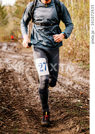athlete runner running on iimpassability dirt road autumn marathon, sports number on leg jogger athlete runner running on iimpassability dirt road autumn marathon, sports number on leg jogger 101872635