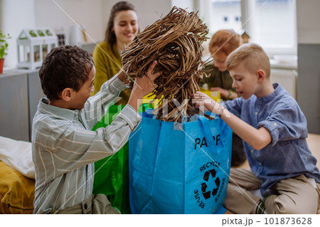 Children with teacher separating rubish in to three bins. 101873628