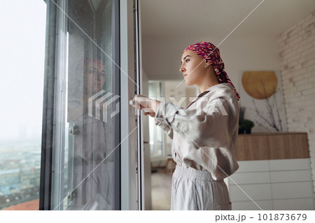 Young unhappy woman with cancer standing in front of a window. 101873679