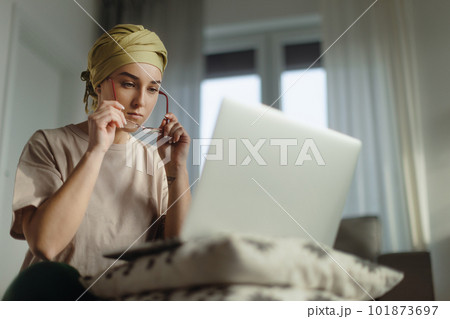 Young woman with cancer working on laptop in her apartment. 101873697