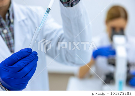 Male scientist analyzes liquid female researcherworking with microscope investigating medical sample 101875282