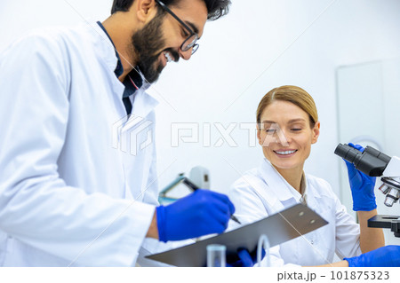 Woman and man scientists in lab coat making notes after doing sample test in laboratory. 101875323