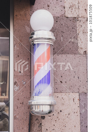 Barber sign and male hairdresser pole or staff mounted on wall. Helix of colored stripes red white and blue Barber sign and male hairdresser pole or staff mounted on wall. Helix of colored stripes red white and blue 101875509