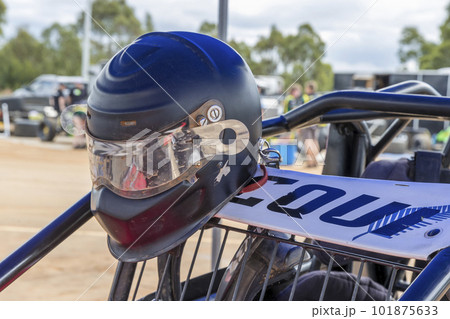 A well-worn helmet hanging on a speedway race car in the pits 101875633