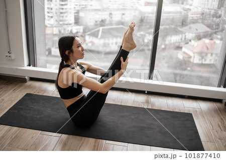 Fit young female training navasana pose indoors 101877410