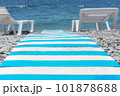 close-up of striped beach path between sun loungers on pebble beach leading to blue sea. summer holiday backdrop. selective focus 101878688