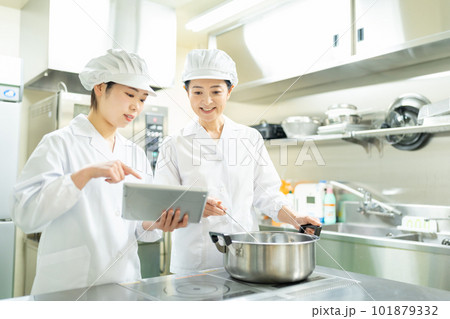 タブレットを見ながら料理する調理師の女性 タブレットを見ながら料理する調理師の女性 101879332