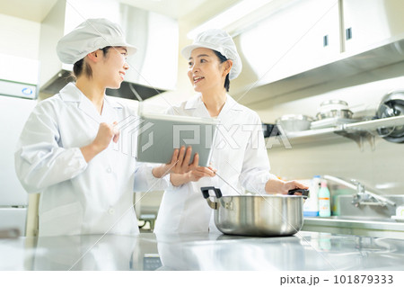 タブレットを見ながら料理する調理師の女性 101879333