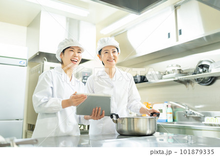 タブレットを見ながら料理する調理師の女性 101879335