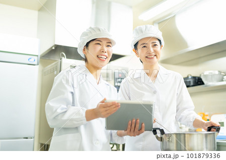 タブレットを見ながら料理する調理師の女性 101879336
