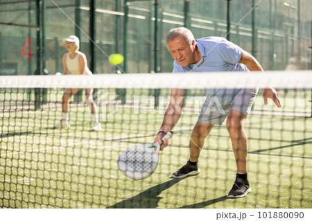 Old man playing Padel Tennis in open-air tennis court 101880090