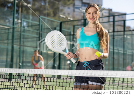 Young happy woman standing in padel court getting ready for match Young happy woman standing in padel court getting ready for match 101880222
