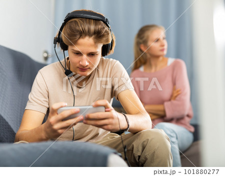 Teen boy with smartphone not paying attention to upset mother 101880277