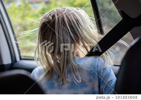 Rear view of teenage sitting in car looking throw open window on roadtrip. 101883608