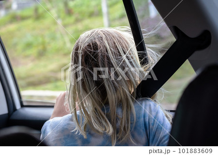 Rear view of teenage sitting in car looking throw open window on roadtrip. Rear view of teenage sitting in car looking throw open window on roadtrip. 101883609