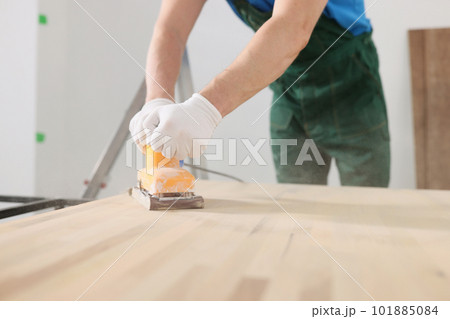 Skilled carpenter polishes wooden surface of office table 101885084