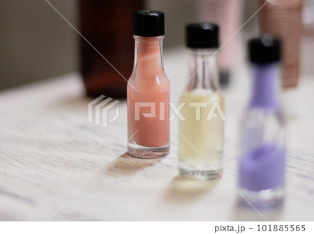 Three small bottles of colourful cream in a row with copy space. Wellness product on table. Bathroom concept. Cosmetic product. Healthy lifestyles. Tonic and lotion in bottles. 101885565