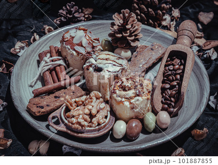 Bakery, Stick cookies, Walnuts, Roasted coffee beans and Colored eggs with Pine cones on Ceramic plate. Bakery, Stick cookies, Walnuts, Roasted coffee beans and Colored eggs with Pine cones on Ceramic plate. 101887855