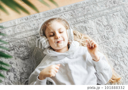 Little girl listening music lying on the floor 101888332