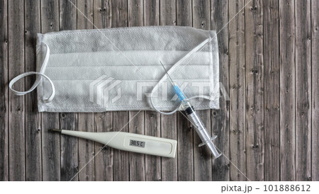 Sterile medical masks, vaccine vial and glass thermometer on a wooden background with copy space 101888612
