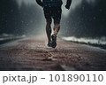 Man running on mud track. Athlete running fast in a park with dense trees in the background. 101890110