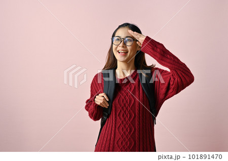 Smiling Asian female college student looking away from camera with hand above her eye Smiling Asian female college student looking away from camera with hand above her eye 101891470
