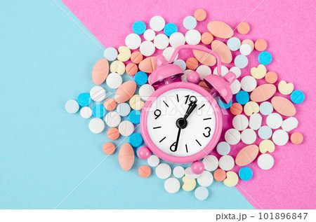 The alarm clock and many drug on a pink colour background. Taking medicine at the right time concepts. The alarm clock and many drug on a pink colour background. Taking medicine at the right time concepts. 101896847