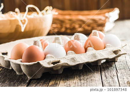 Whole chicken eggs in eggbox on wooden table. 101897348