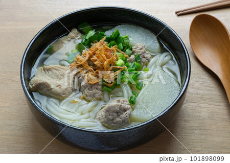 close up view of vietnamese rice noodles soup with pork in a ceramic bowl on wooden table. asian homemade style food concept. close up view of vietnamese rice noodles soup with pork in a ceramic bowl on wooden table. asian homemade style food concept. 101898099