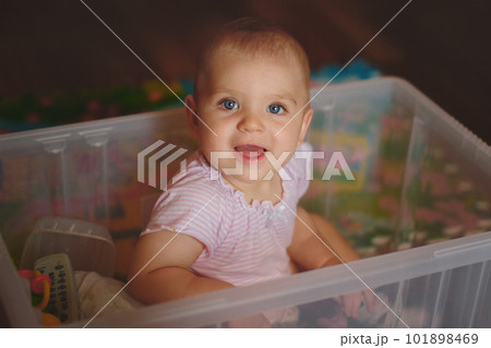 Baby in pajamas sits in basket of toys and smiles 101898469