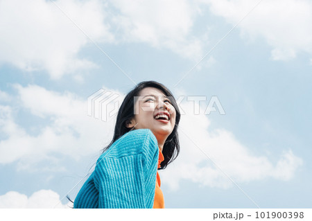 楽しげな表情で青空を見上げる20代のかわいい女性 101900398
