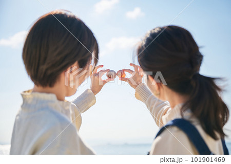 砂浜で拾った貝を高く掲げる若い女性の手 砂浜で拾った貝を高く掲げる若い女性の手 101901469