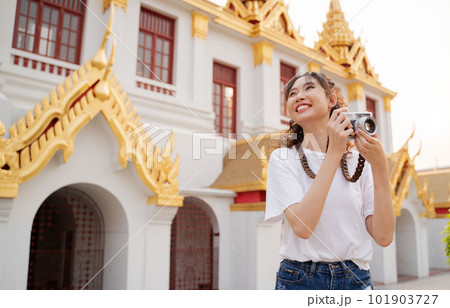 Asian woman tourist backpacker smiling, traveling and taking photo with temple background in Bangkok, Thailand. Asian people excited and having fun traveling. Asian woman tourist backpacker smiling, traveling and taking photo with temple background in Bangkok, Thailand. Asian people excited and having fun traveling. 101903727