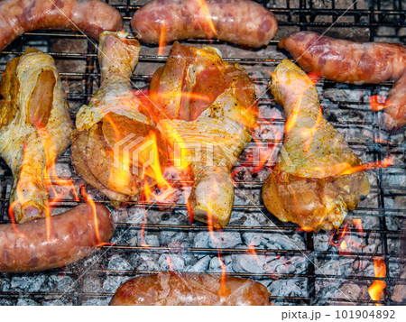 Chicken legs and meat sausages on an iron barbecue net over the fire. Chicken legs and meat sausages on an iron barbecue net over the fire. 101904892