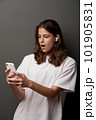 Surprised teen female in earbuds and looking at smartphone in hands 101905831