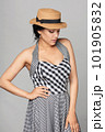 Pensive mixed race woman in chequered summer dress and canotier straw hat 101905832