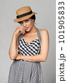 Mixed race woman in chequered summer dress and canotier straw hat 101905833