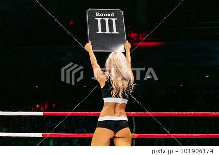 blonde ring girl demonstrate sign with number third round during fight MMA on dark background 101906174